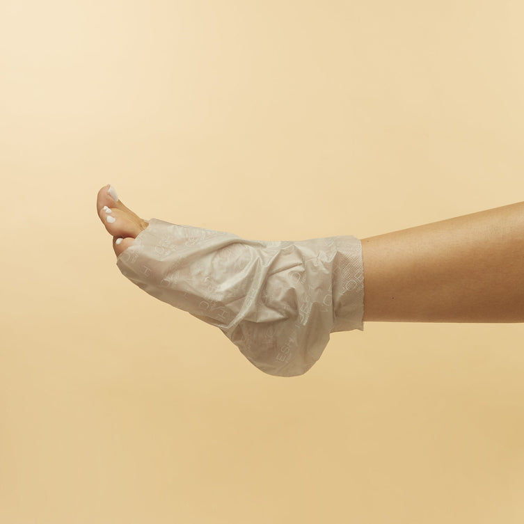 Woman's foot wearing Collagen Socks with Hemp Oil tip removed on orange background